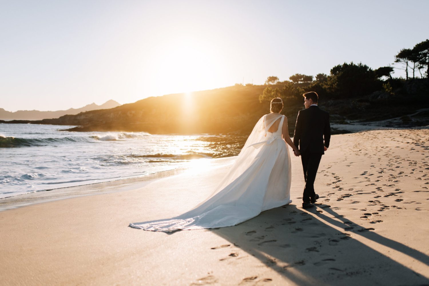 Just married couple walking by the beach at sunset
